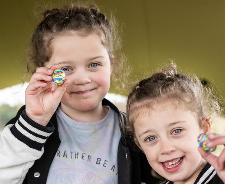 Two girls smiling and holding a mini Easter egg