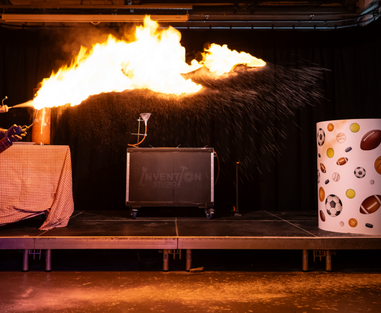 Oli stood on the science theatre stage, wielding a giant flame.