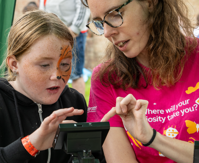 Inspirer showing a child how to use a microscope.