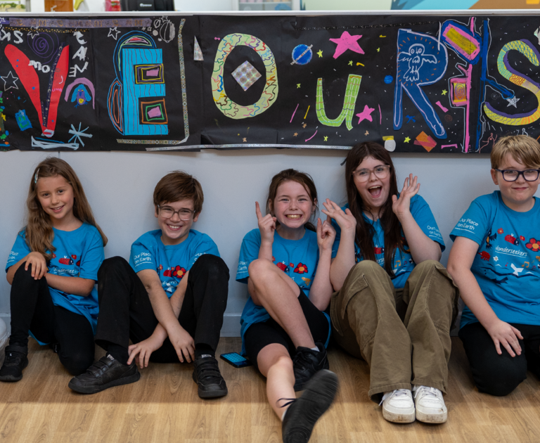 Our Young Design Panel are sat in front of a banner that reads "save our sky". They are all smiling.