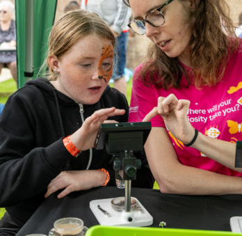 Inspirer showing a child how to use a microscope.