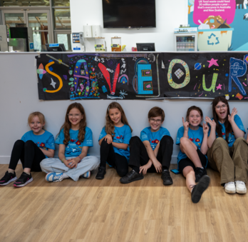 Our Young Design Panel are sat in front of a banner that reads "save our sky". They are all smiling.