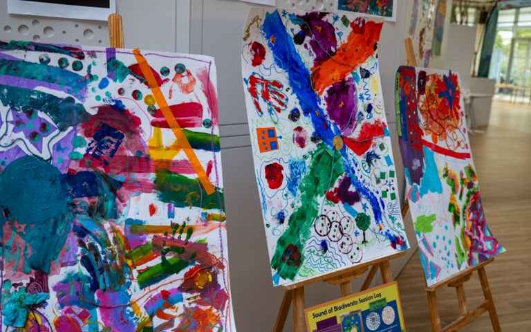 artwork made up of ink splatters and coloured tape displayed on two wooden easels.