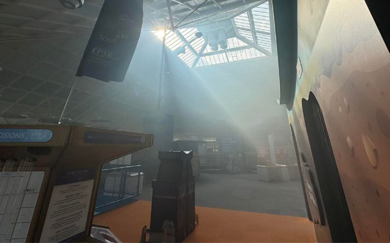 The roof of the pyramid building is filled with smoke. Sun is shinning through the windows and smoke. The exhibit are very hard to see through the smoke.