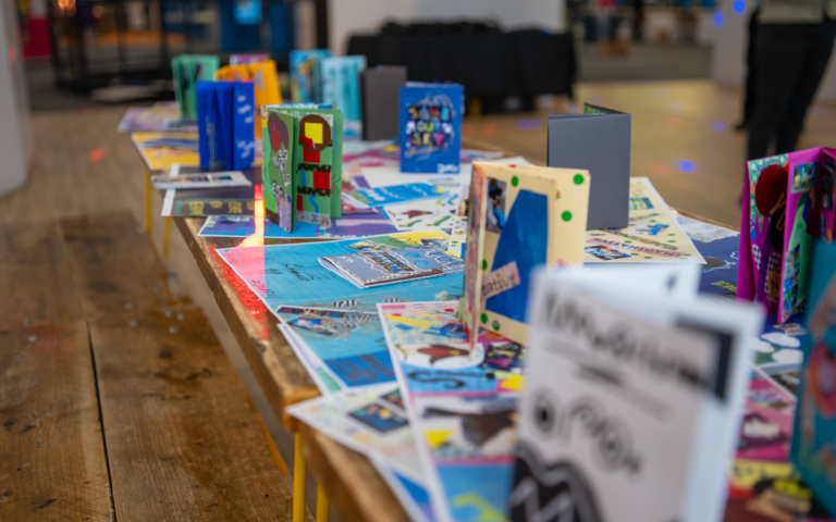 A selection of colourful artwork spread across a table.