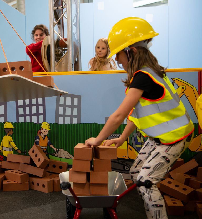 A child wearing a high visibility jacket building with foam bricks